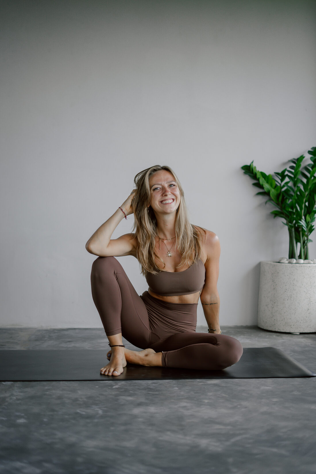 Michelle smiling, sitting relaxed on her yoga mat