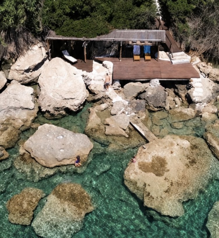 Aerial view of the private wooden deck on the rocks above turquoise water