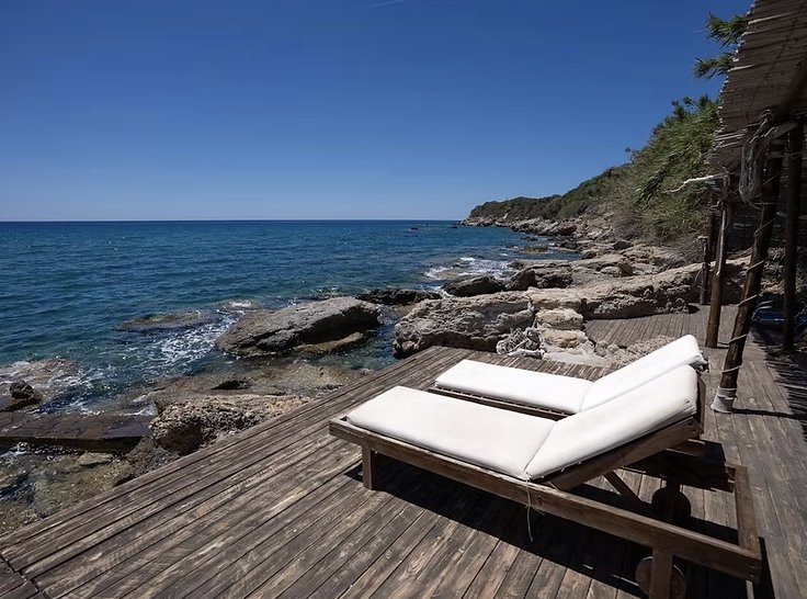 Sun loungers on the private wooden deck above the rocks and sea
