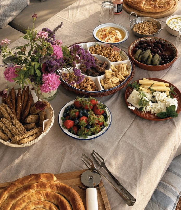 A shared table of Greek dishes, fruit, cheese and fresh bread